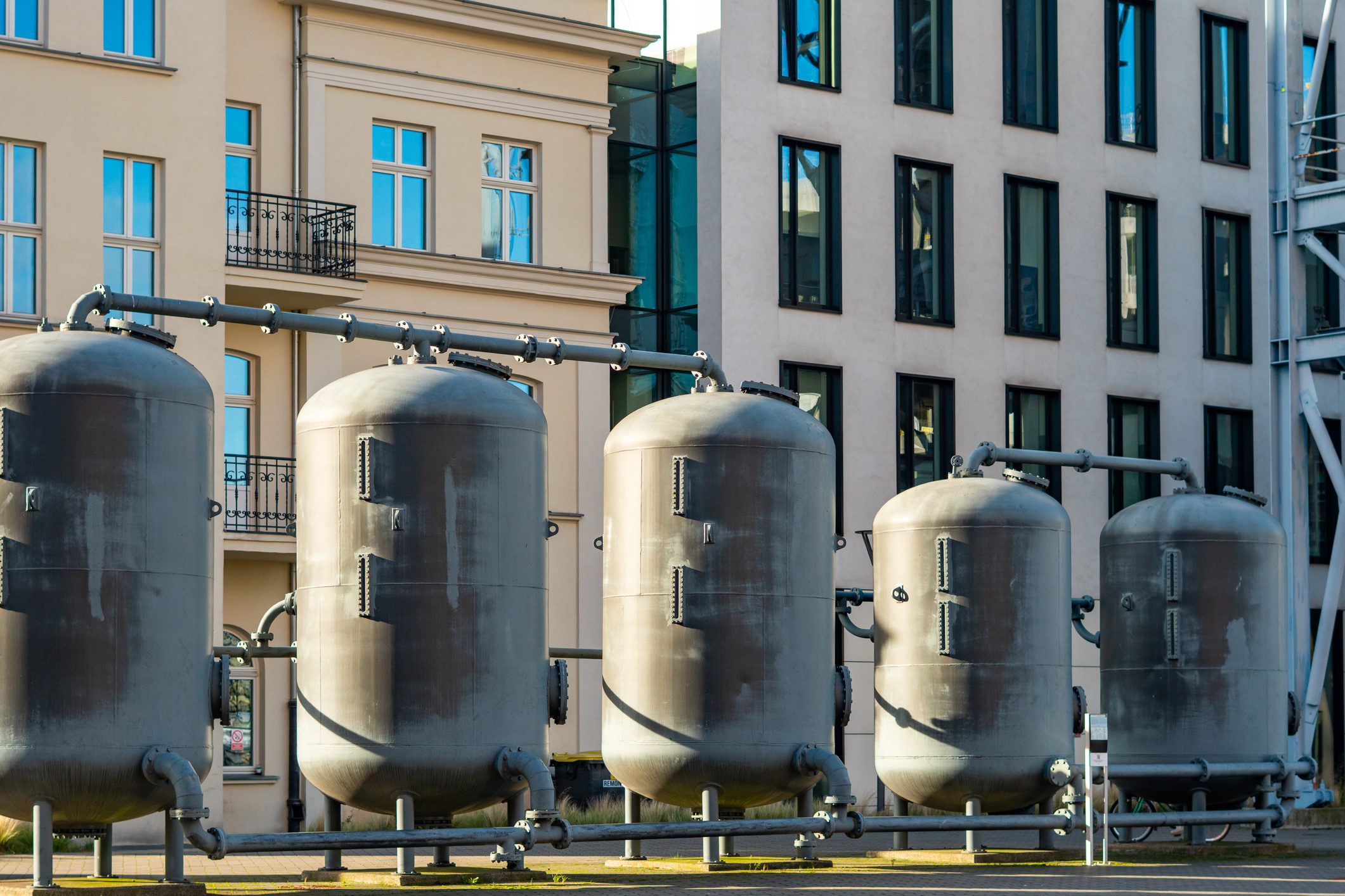 Industrial tanks in front of modern buildings.