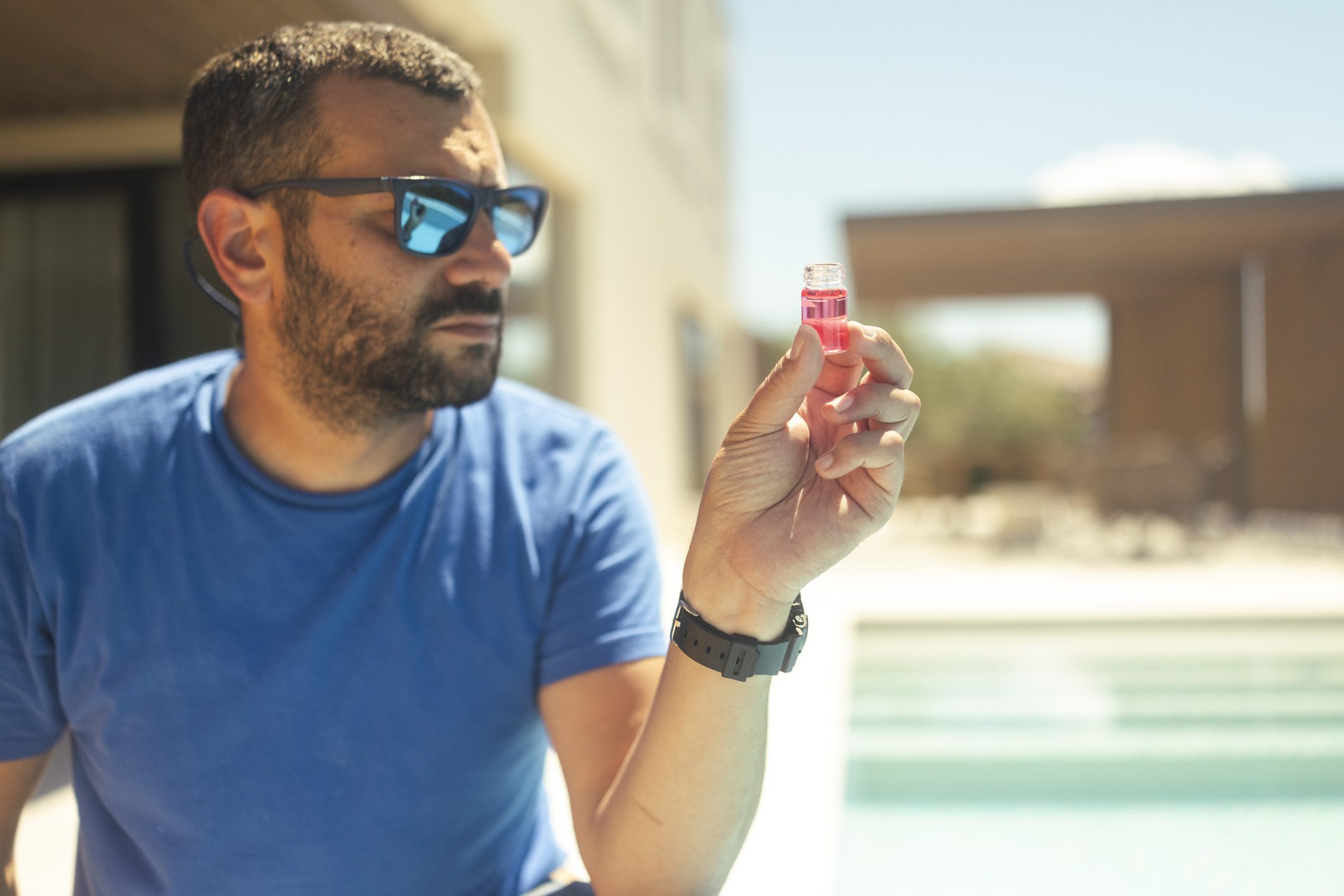 Man examining a small red vial outdoors.