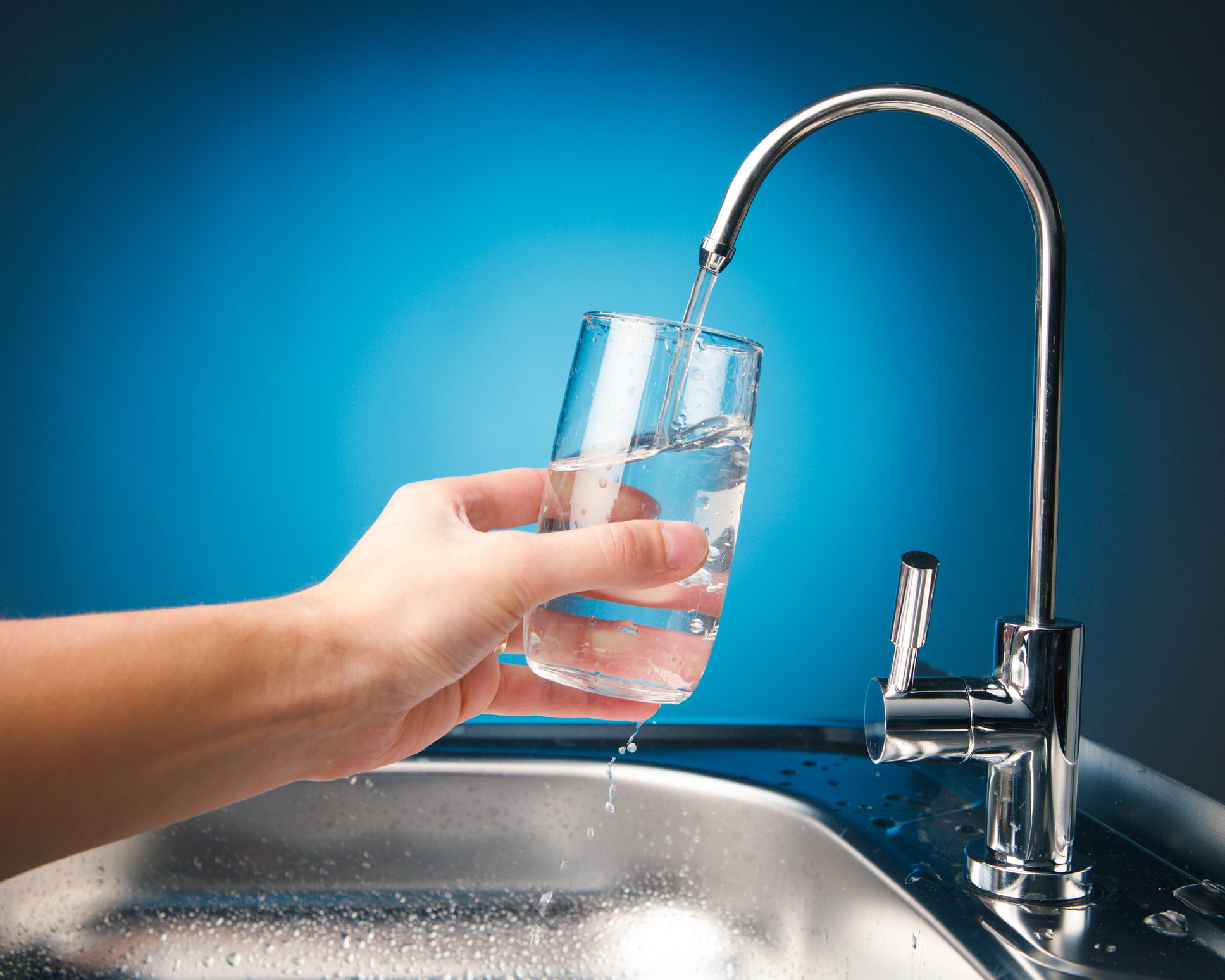 Hand filling glass with water from faucet.