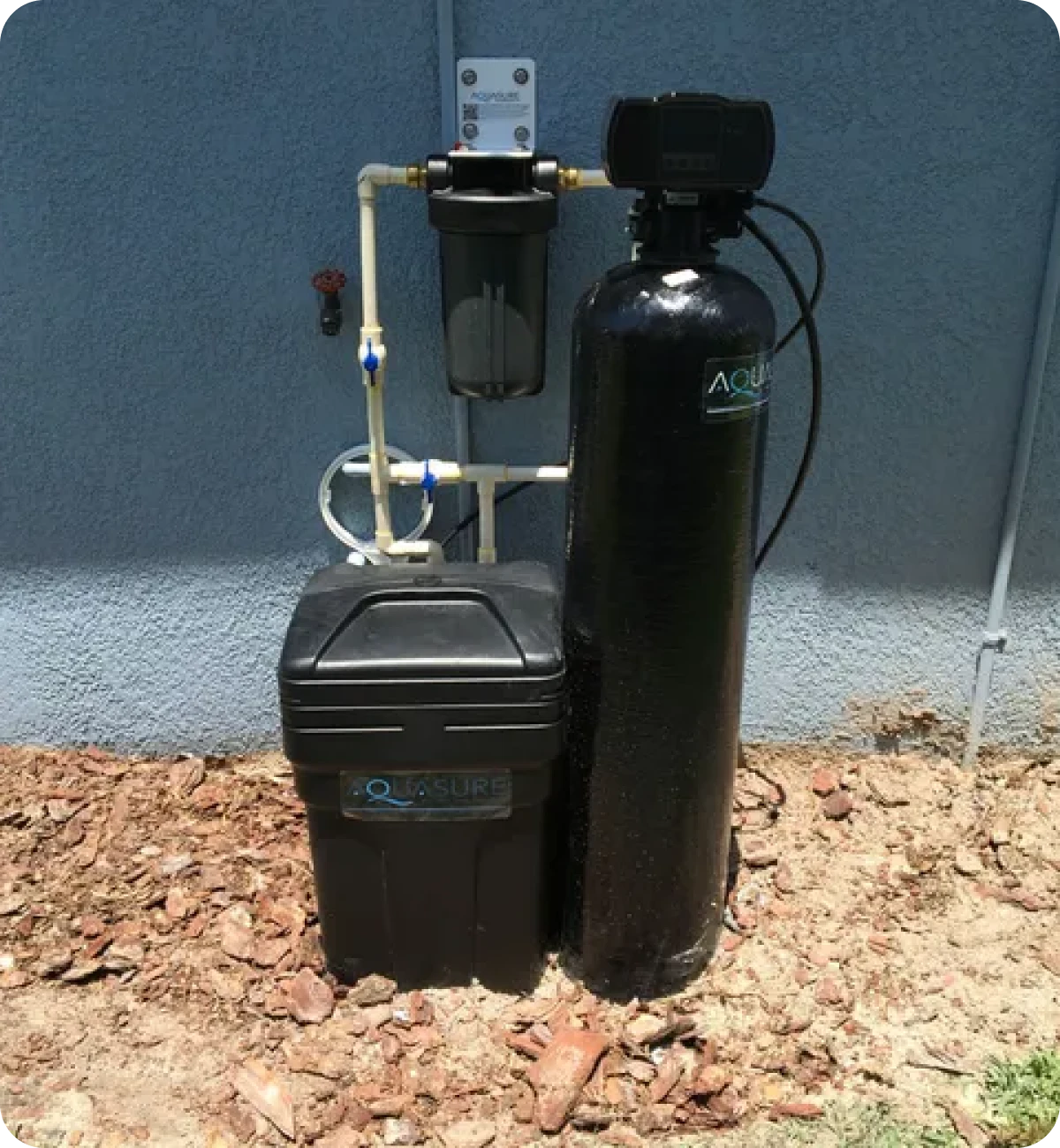 Water filtration system installed outdoors against wall.